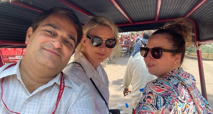 Drei Personen in einer Rikscha mit dem sichtbaren Fahrer vorne.