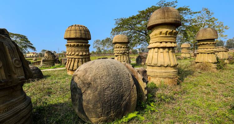 Field with large carved stone structures under a blue sky.