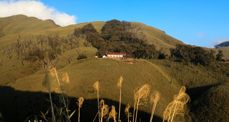Isolated building set on a hill surrounded by rolling hills and blue sky.