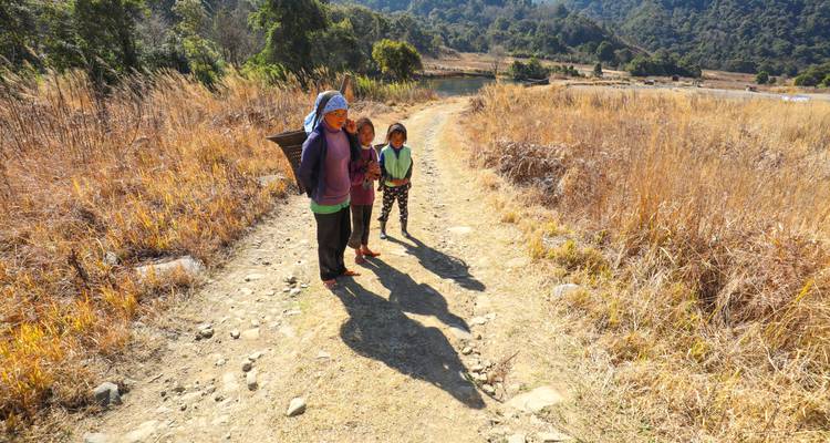 Two people walking on a dirt path in a dry field.