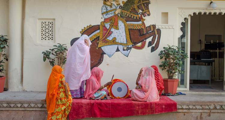 Vrouwen in traditionele kleding die muziek spelen voor een Indiase muurschildering.
