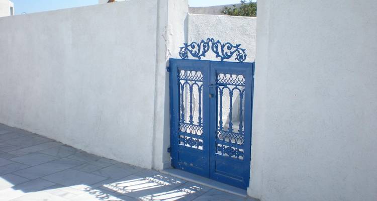 Puerta de hierro forjado azul colocada en una pared blanca.