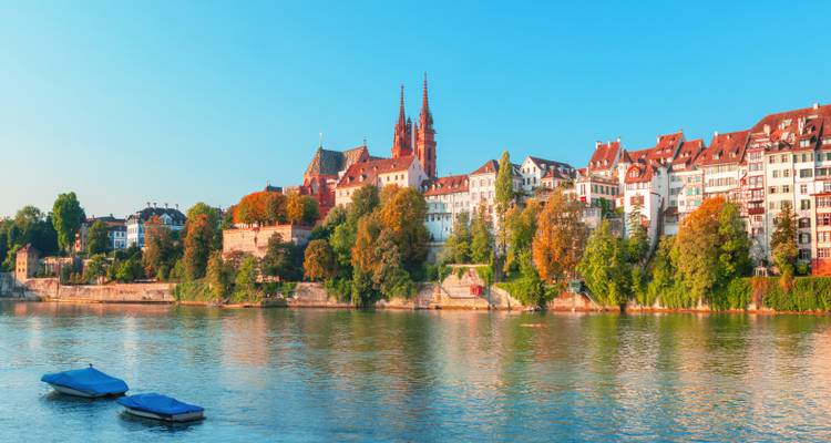 Vaste panorama fluvial de la silhouette historique de Bâle sous la lumière matinale bleu ciel avec de petits bateaux sur le Rhin