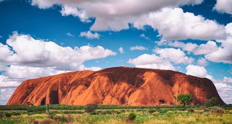 Majestic red rock formation under a blue sky with clouds.
