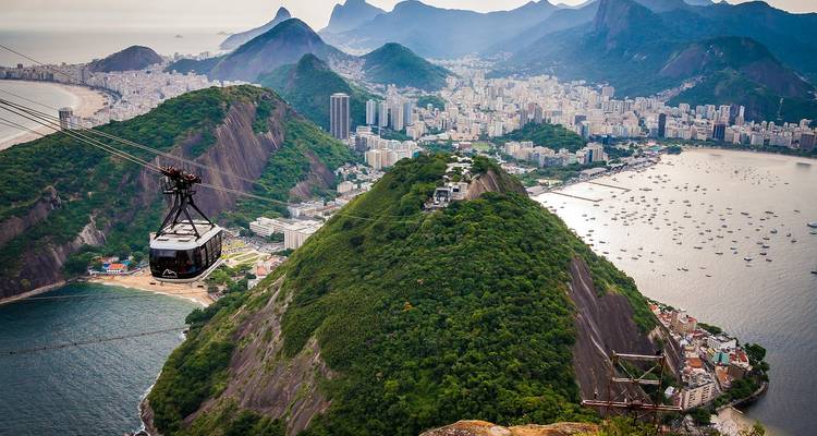 Cable car ascending Sugarloaf Mountain with panoramic city and coastline views below.