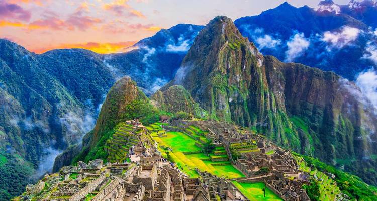 Iconic terraces of Machu Picchu perched on lush mountain ridge against dramatic sunrise sky
