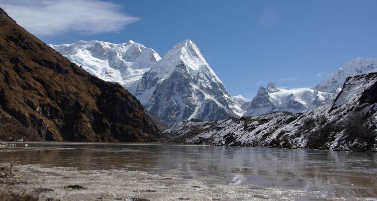 Besneeuwde bergen met een gedeeltelijk bevroren rivier op de voorgrond.