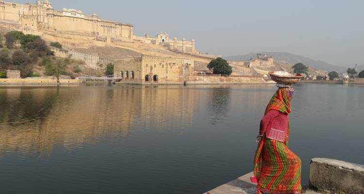 Femme en tenue traditionnelle près d'un fort et d'un lac.