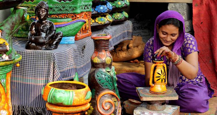 Femme décorant de la poterie sur un marché.