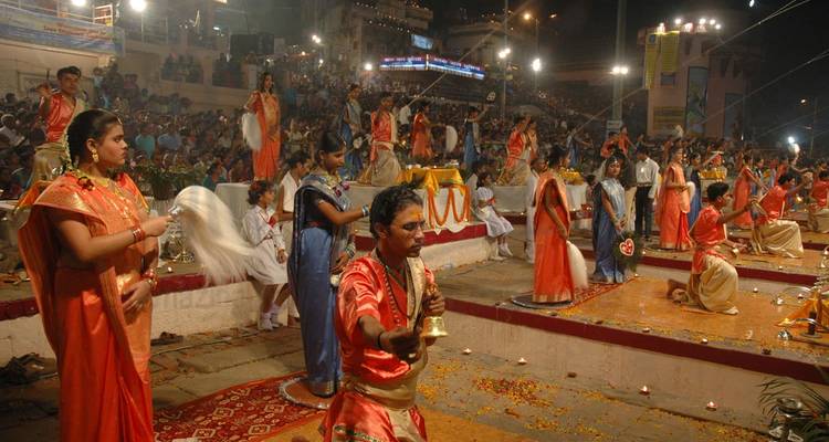 Evening ritual ceremony by the river with crowds.