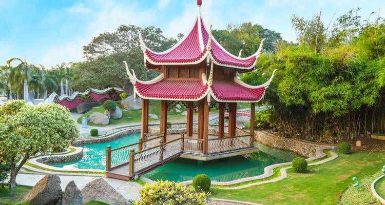 Pabellón ornamentado sobre un estanque en un entorno de jardín tranquilo.