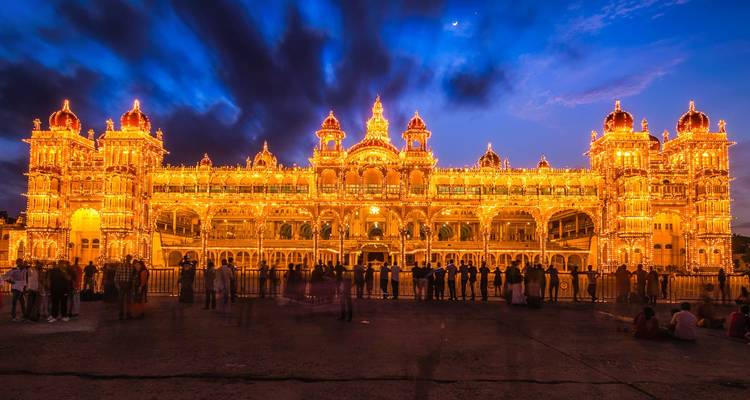 Mysore-Palast hell erleuchtet und am Abend von Menschen umgeben.