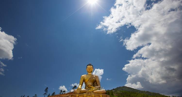 Gran estatua de Buda bajo un cielo iluminado por el sol.