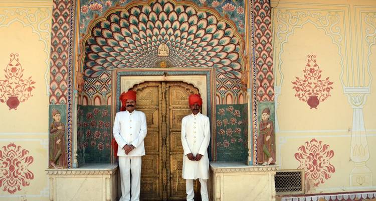 Twee mannen in traditionele kleding die bij een prachtig versierde deuropening staan.