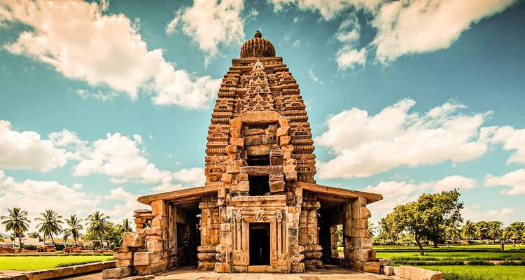 Oude stenen tempel met levendige lucht en groen.