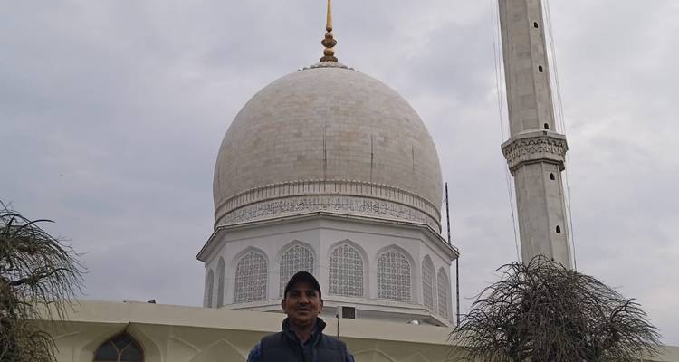 Une personne debout devant une mosquée blanche avec un grand dôme et un minaret.