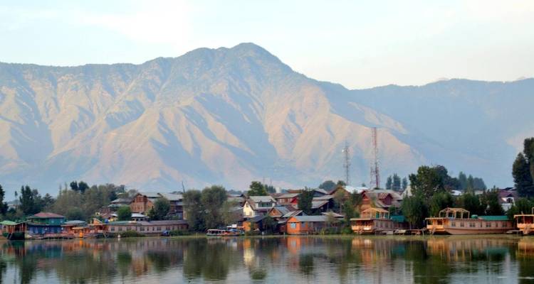 Un lac serein avec des péniches et un arrière-plan montagneux.
