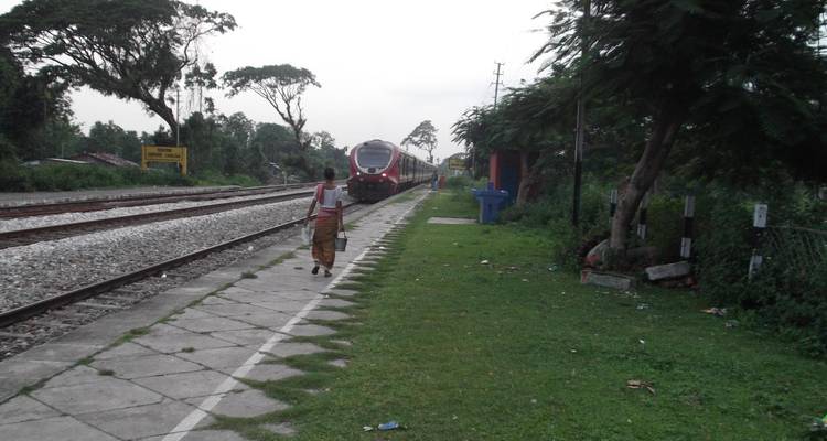 A person walking along a railway track with a train approaching.