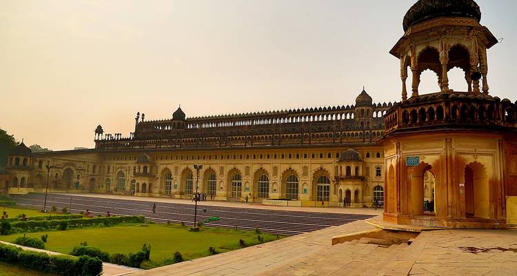 Un gran edificio histórico con un jardín bajo un cielo suave.