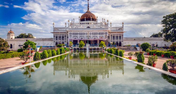 Un edificio blanco impresionante con una piscina reflectante bajo un cielo nublado.