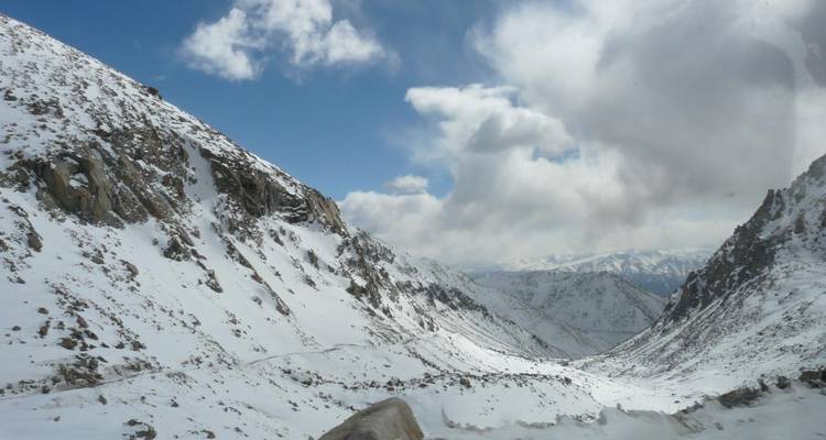 Schneebedeckter Bergpass unter bewölktem Himmel.