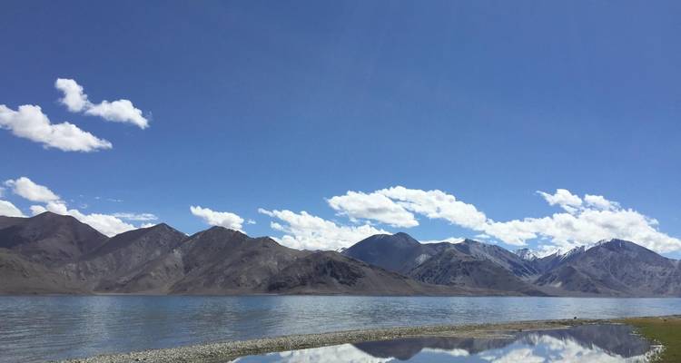 Bergsee mit spiegelndem Wasser unter einem strahlend blauen Himmel.