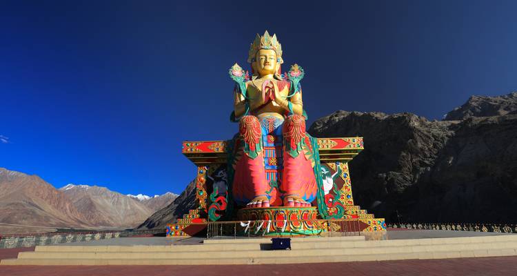 Große bunte Buddha-Statue vor einer bergigen Landschaft