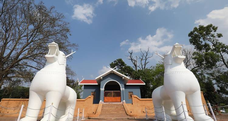 Ingang van een bouwwerk bewaakt door twee grote witte beelden.