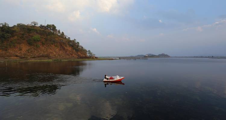 Rode boot op een serene meer met heuvelachtige omgeving.