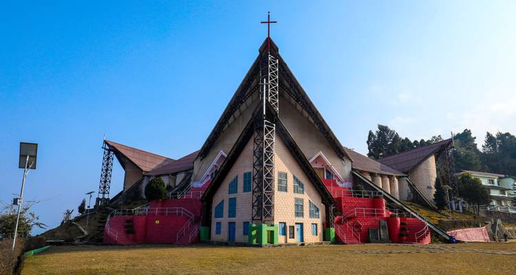 Modern kerkgebouw met rode en groene elementen tegen een blauwe hemel.