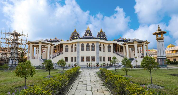 Witte tempel met sierlijke architectuur en bewolkte lucht op de achtergrond.