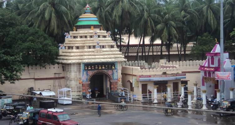 Entrée d'un complexe de temples entourée d'une végétation luxuriante, présentant une architecture indienne classique.