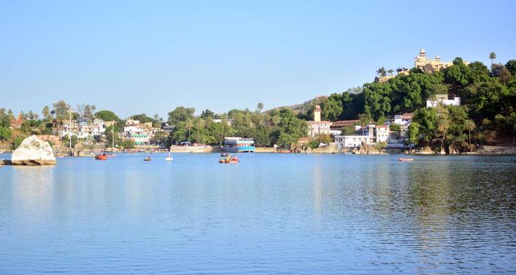 Lake with colorful boats and hillside buildings.