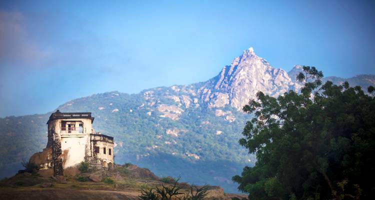 A solitary building with a majestic mountain in the background.