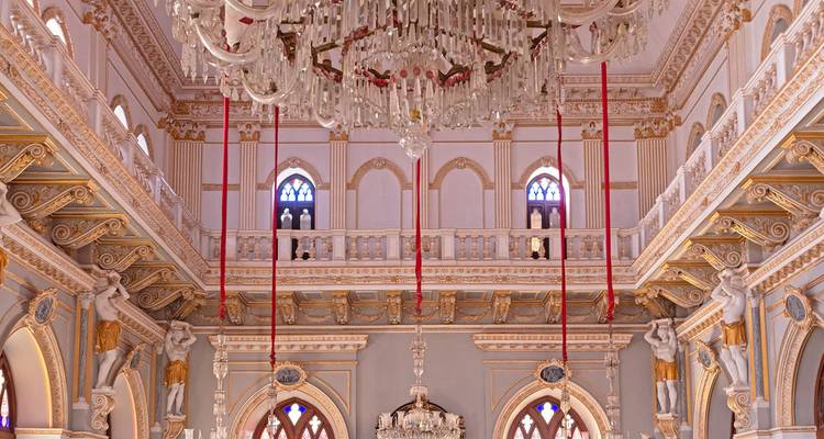 Kunstvolles Interieur einer großen Halle mit Kronleuchtern und Bögen.