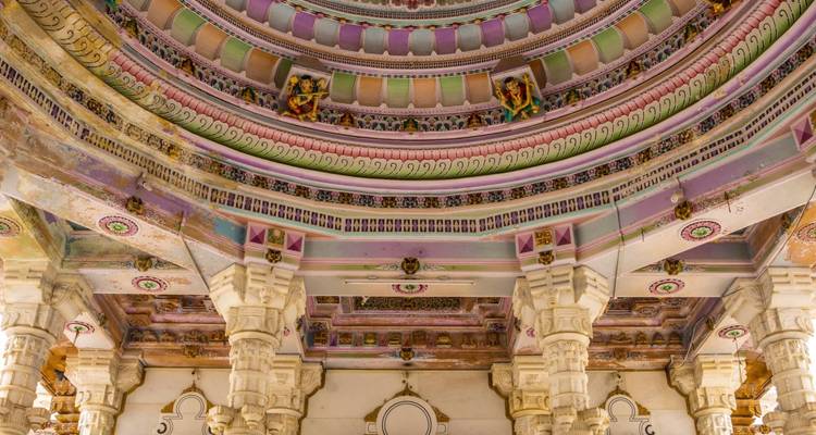 Ingewikkeld beschilderd plafond van een tempel met sierlijke zuilen.