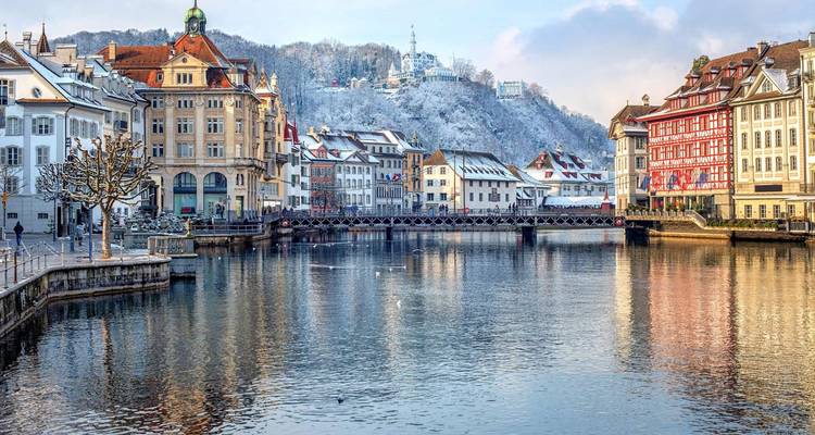 Une ville suisse pittoresque au bord de l'eau avec de la neige sur les collines en arrière-plan.