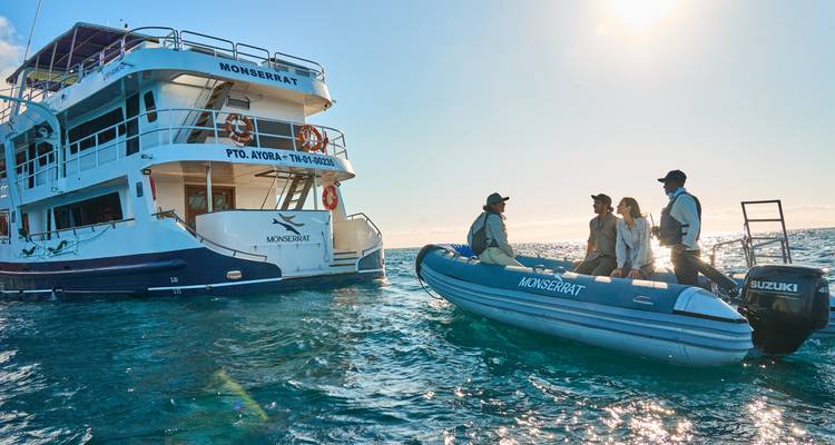 Grupo de personas en un bote pequeño cerca de una embarcación más grande.