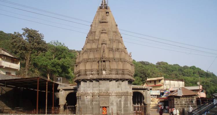 Tall temple structure with a pointed roof surrounded by trees.