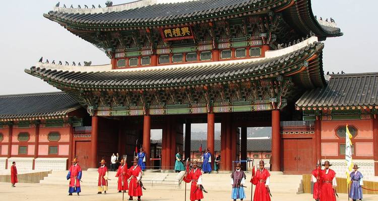 Traditionelle koreanische Wachen, die vor einem historischen Palastgebäude stehen.