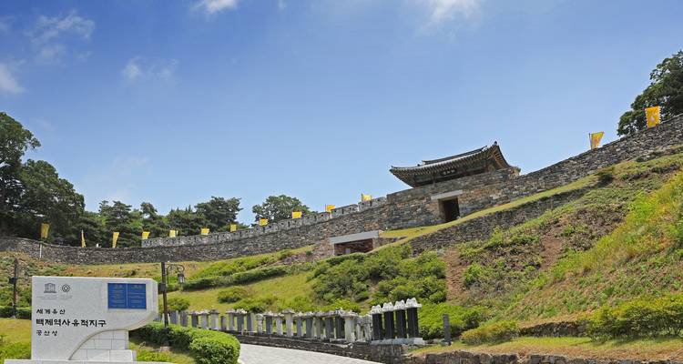 Steinwälle und Tor der von der UNESCO gelisteten Festung Gongsanseong unter blauem Himmel.
