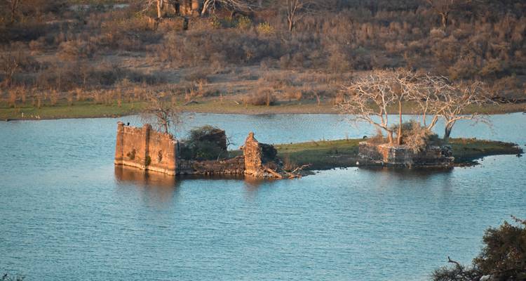Ruined structure on an isolated island in a body of water.