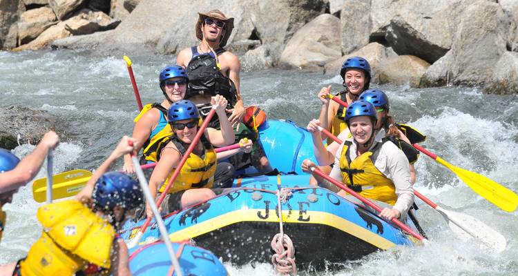 A group of people enjoying whitewater rafting on a river surrounded by rocks.