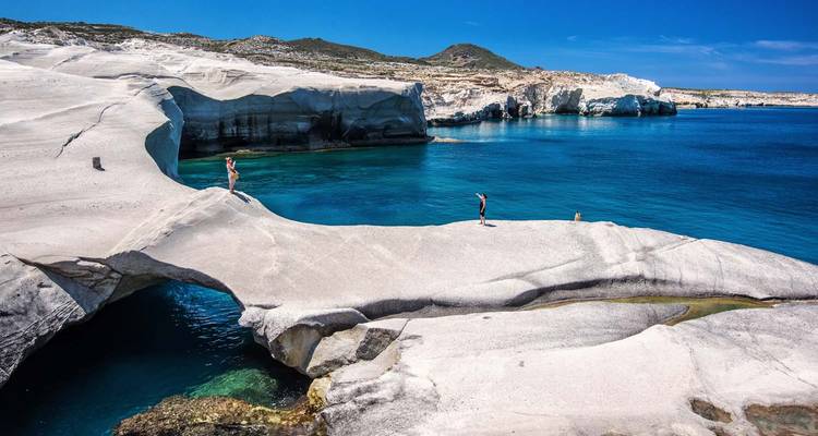 Stunning rock formations with people exploring by the sea in Milos.