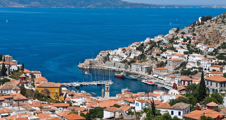 Ville côtière avec un port, des collines et des bâtiments le long du rivage.