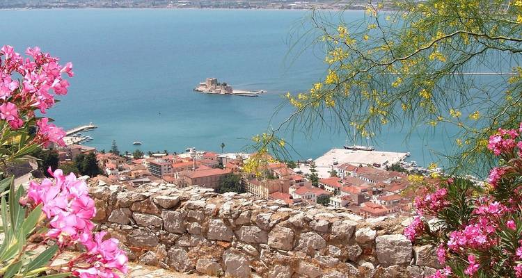 Blick auf eine Stadt von einem Hügel, Blumen und Meer in Sicht.