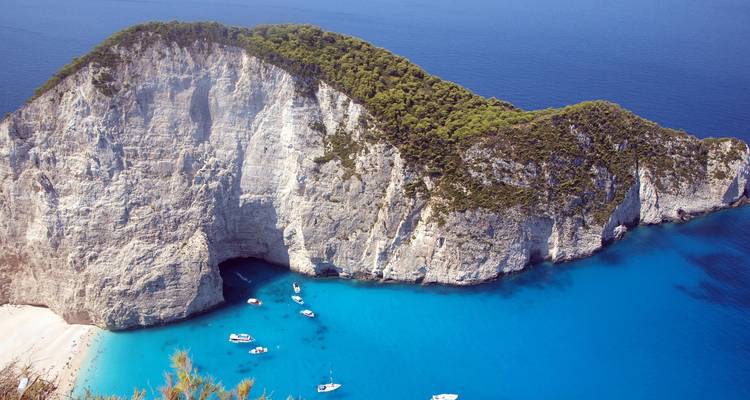 Vue imprenable sur la plage de Navagio avec des bateaux dans les eaux bleues.