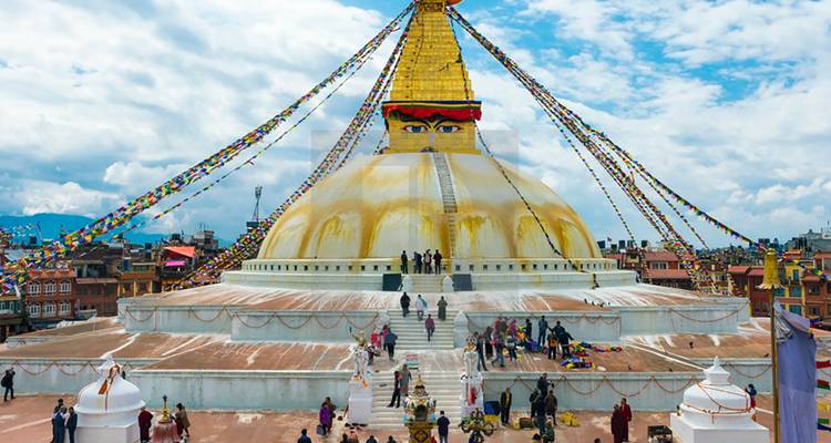 Grote stupa met gebedsvlaggen en mensen op een terrasdak.