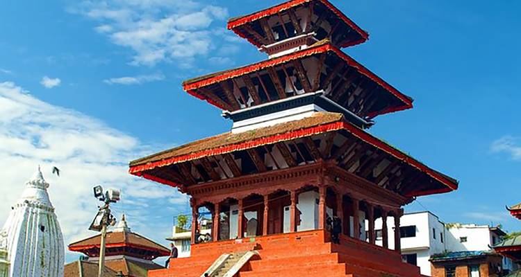 Pagode-stijl tempelgebouw in een stad met blauwe lucht.