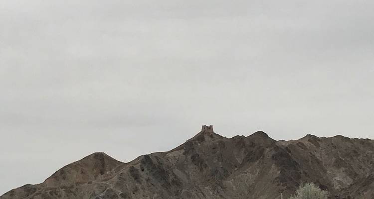 Petite fortification au sommet d'une colline sous un ciel nuageux.